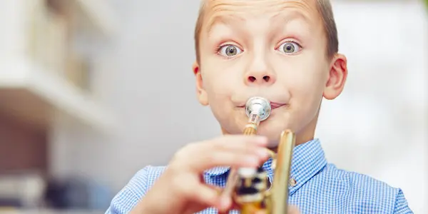 En pojke blåser i en trumpet