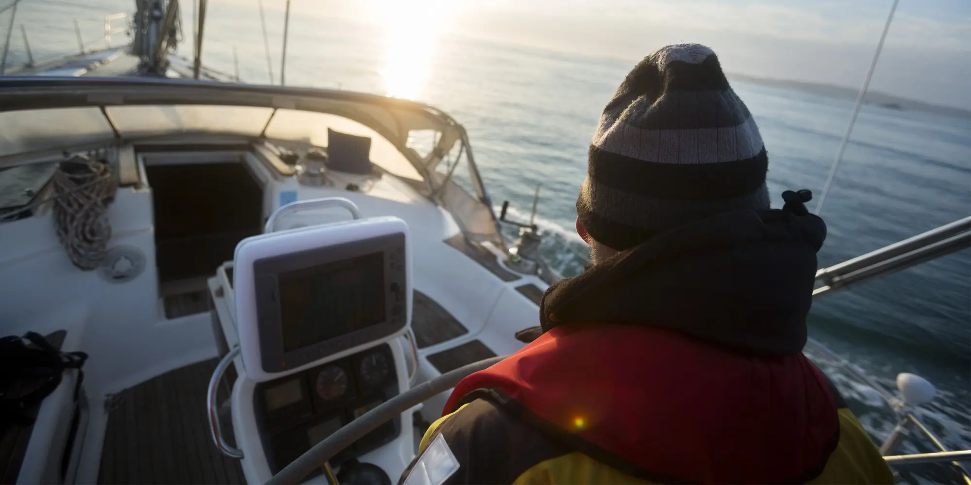 En man styr en båt och blickar ut över havet