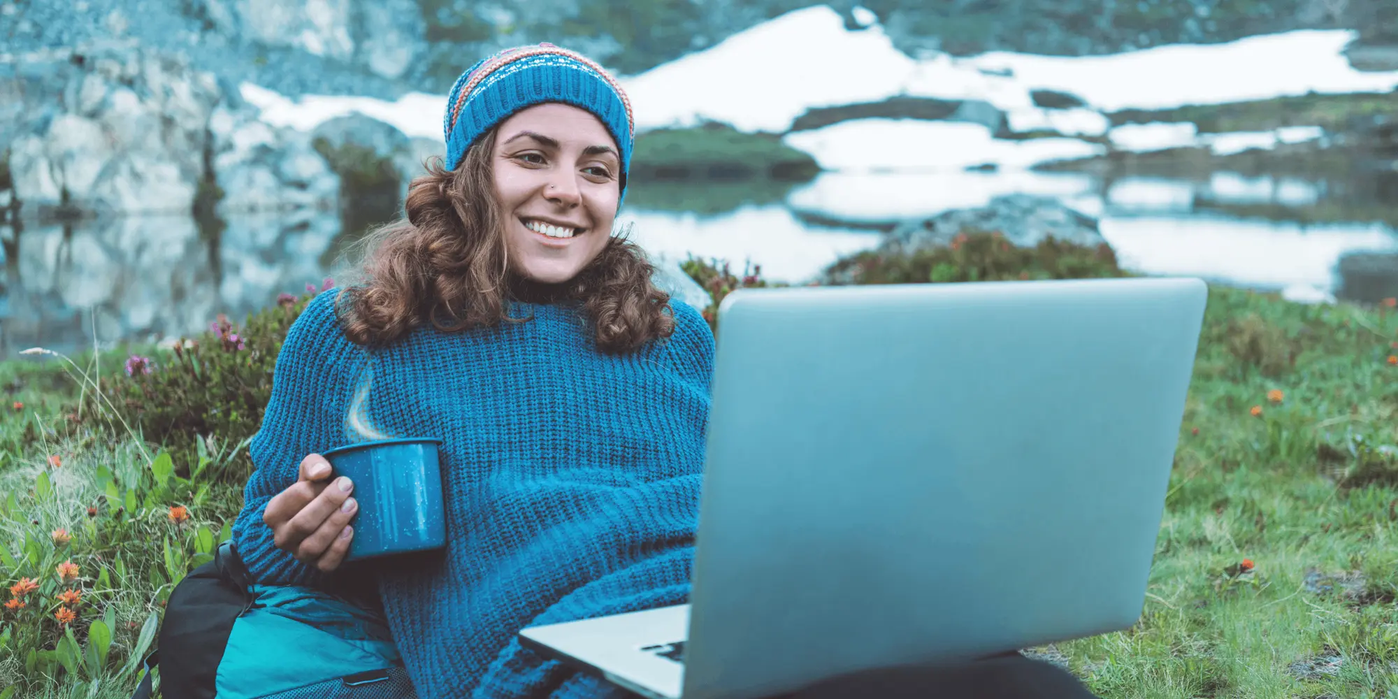 Kvinna som sitter i  naturen och bedriver distansstudier