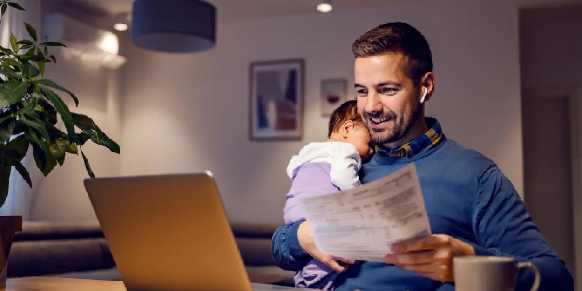 Man som sitter framför laptop med bebis