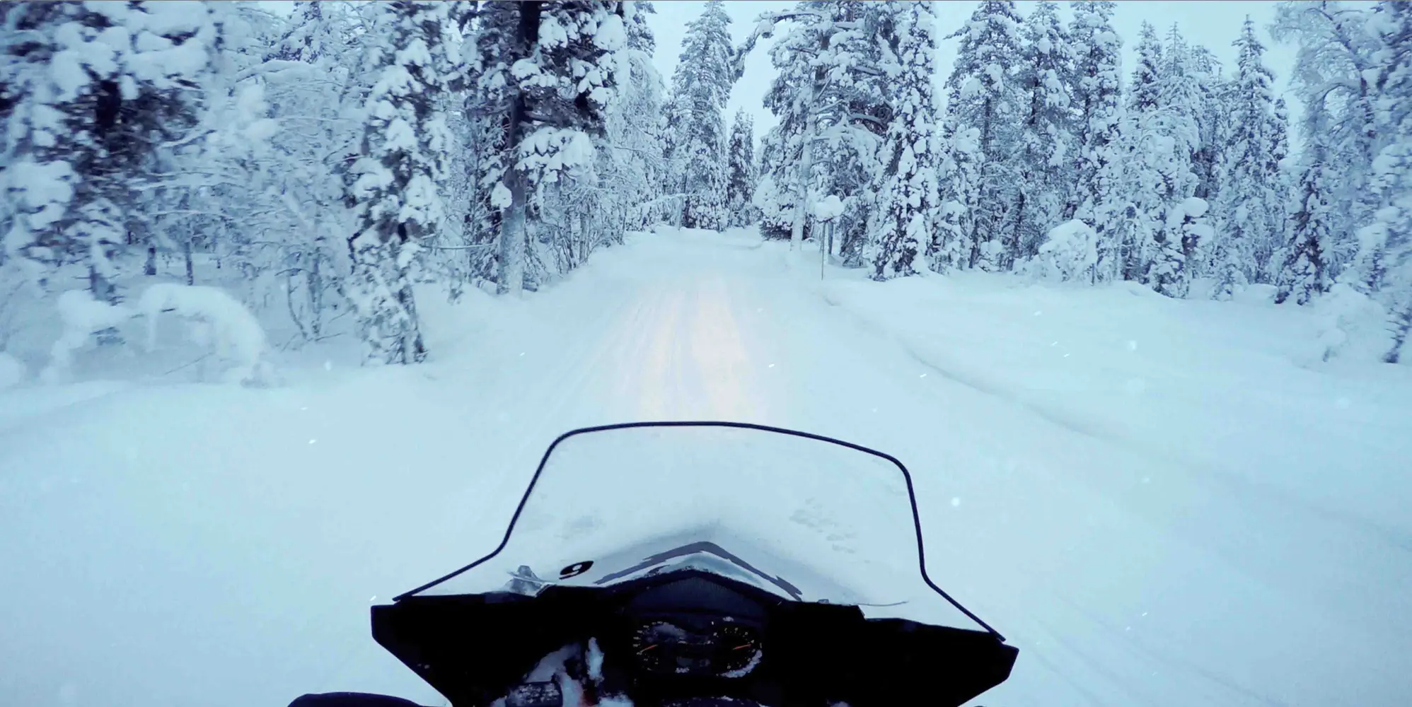 Snöskoteråkning i vinterlandskap.